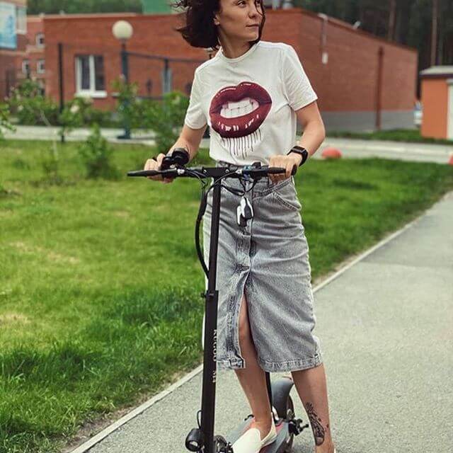 Una joven lleva su patinete eléctrico Kugoo y circula por un parque